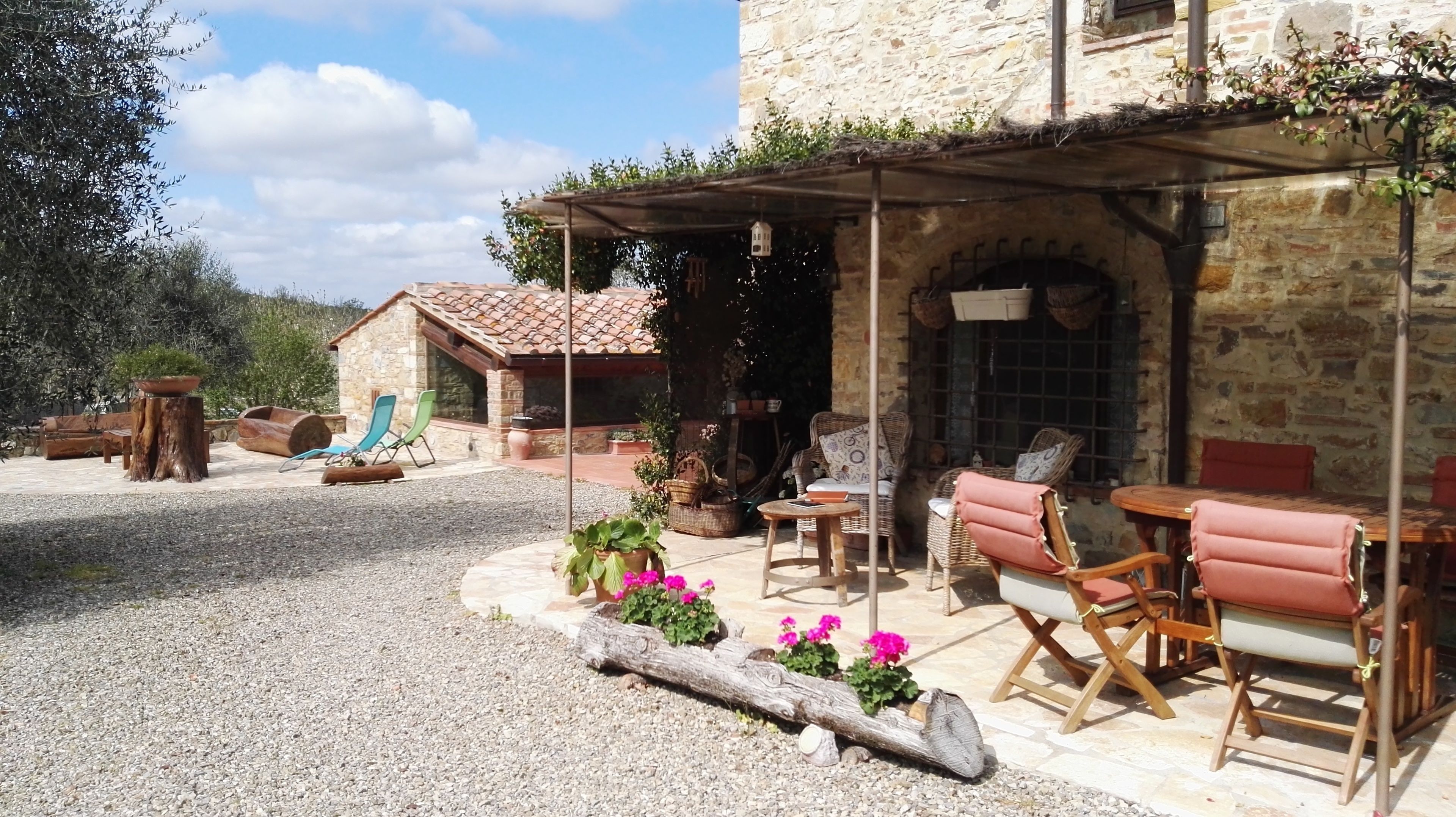 Edificio de piedra con un patio cubierto que cuenta con asientos exteriores y una chimenea de piedra.