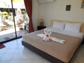 A hotel room with a bed, a window with curtains, a fan, and a view of the outside. - Blue Sky Residence (Patong)