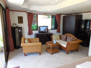 A living room with wicker furniture, a television, and a refrigerator. - Blue Sky Residence (Patong)