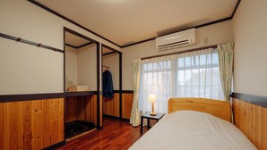 Un dormitorio con cama de madera, mesita de noche con lámpara, armario y ventana con cortinas.