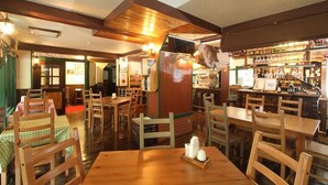A restaurant interior with wooden tables and chairs, a bar area, and a counter with various items. - Hotel Morgenrot (Kobe)