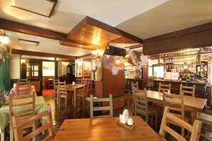 A restaurant interior with wooden tables and chairs, a bar area, and a counter with various items. - Hotel Morgenrot (Kobe)