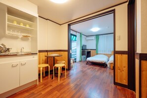A compact room with a kitchenette, a small dining area, and a bed. - Hotel Morgenrot (Kobe)