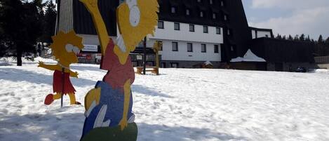 Two large, colorful cardboard cutouts of characters in a snowy outdoor setting with a modern building in the background.