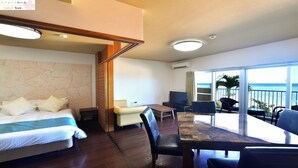 Habitación de hotel con cama, una mesa de comedor y balcón con vista al océano.