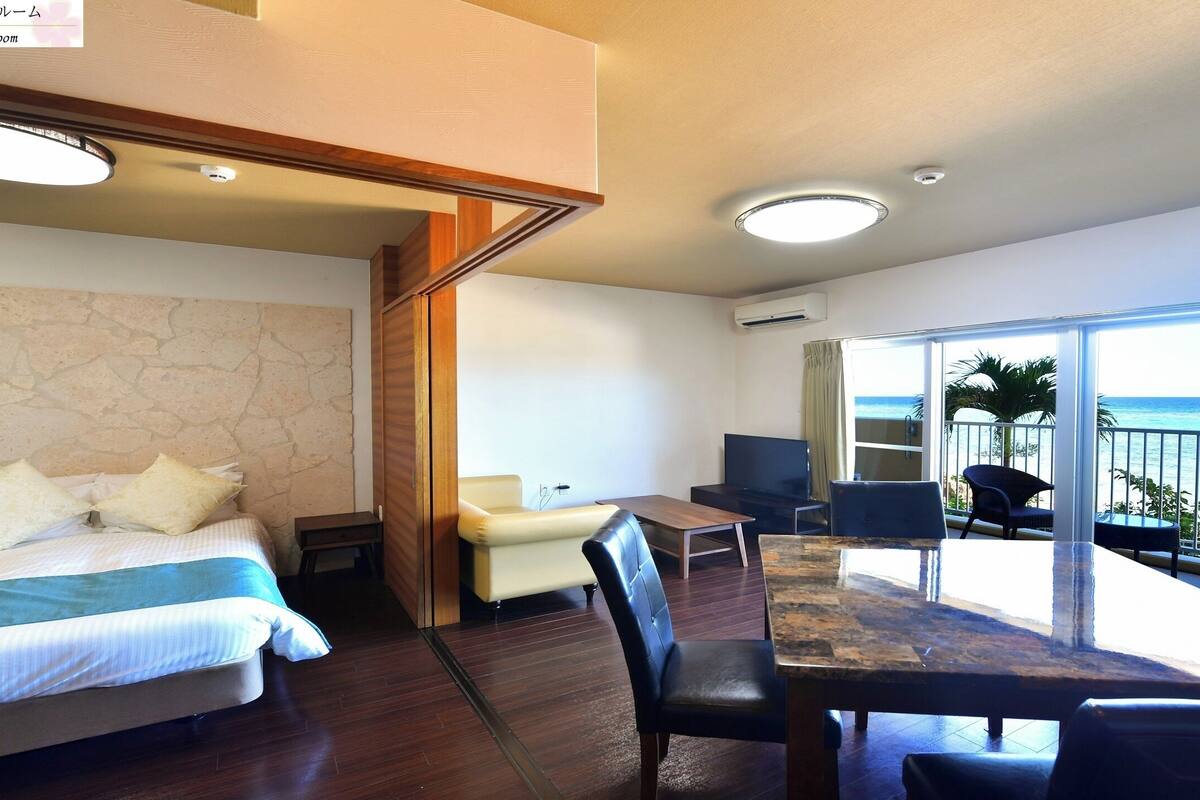 Habitación de hotel con cama, una mesa de comedor y balcón con vista al océano.
