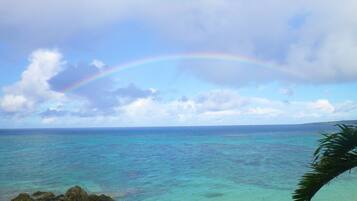 Ein klarer Himmel mit einem Regenbogen über einem türkisfarbenen Meer.