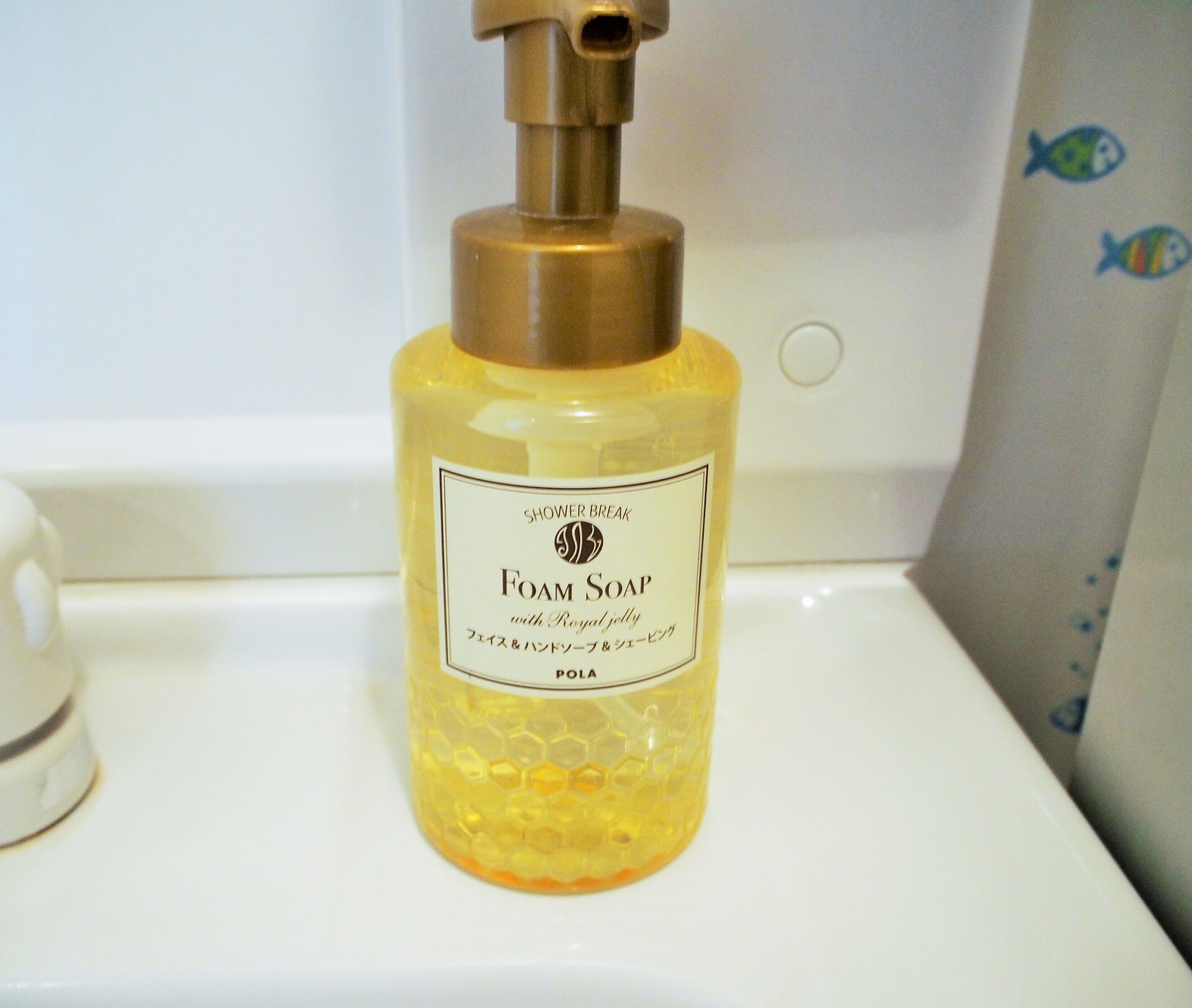 Una botella de jabón espumoso para la ducha con jalea real sobre un lavamanos de baño.