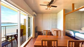 A room with a balcony, a dining table, and a bed.