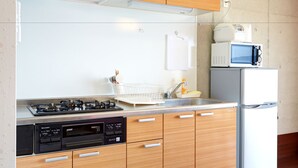 Eine moderne Küche mit Holzschränken, einem eingebauten Gasherd, einer Spülmaschine und einer Mikrowelle.
