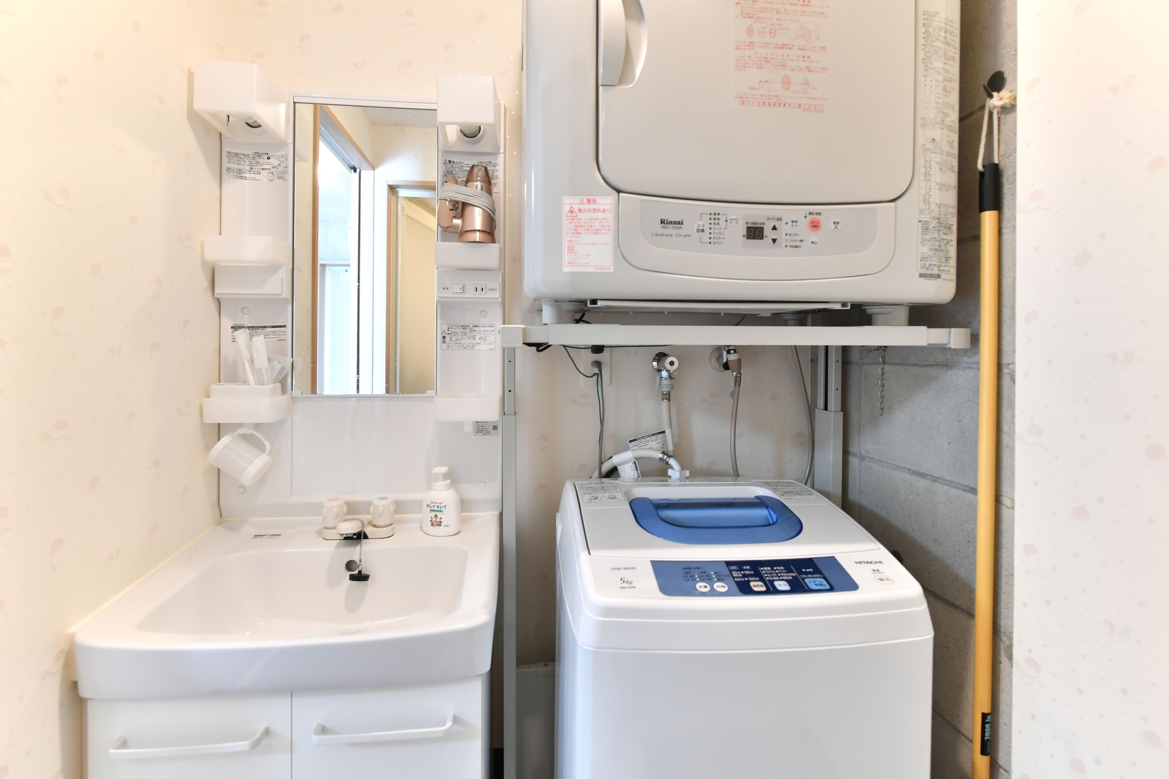 A bathroom with a sink, mirror, and a white washing machine.