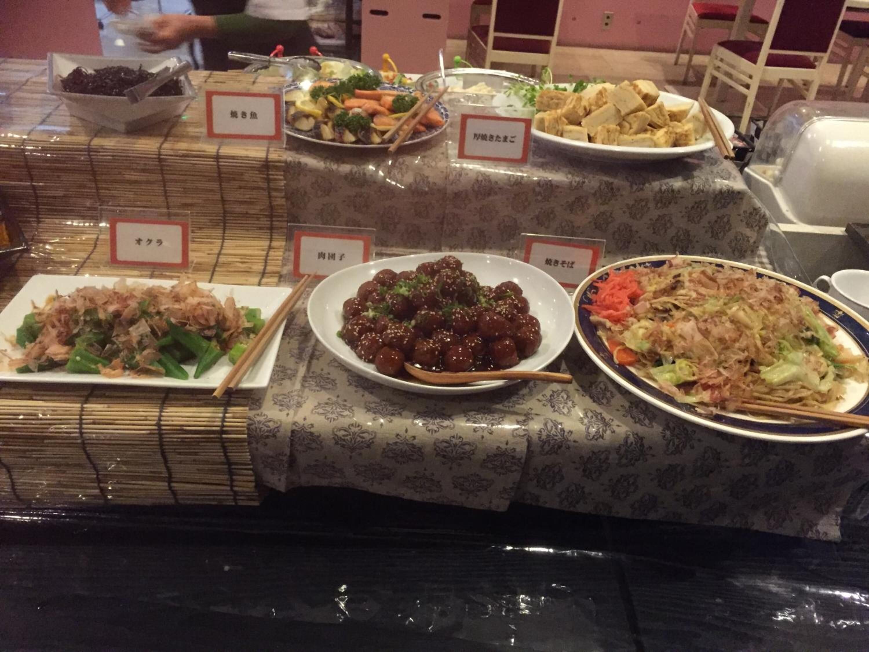 A buffet table with various dishes labeled in Japanese.