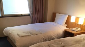 A hotel room with two beds, each with neatly folded towels and a bedside phone. - Hotel Crown Hills Kofu (Kofu)