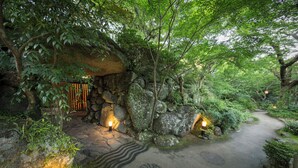Un sendero de piedra bordeado de abundante vegetación e iluminado por una luz tenue.