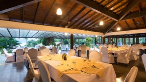 A spacious indoor venue with multiple round tables set for dining, covered by a high ceiling with exposed beams. - Oruthota Chalets (Maberiyatenna)