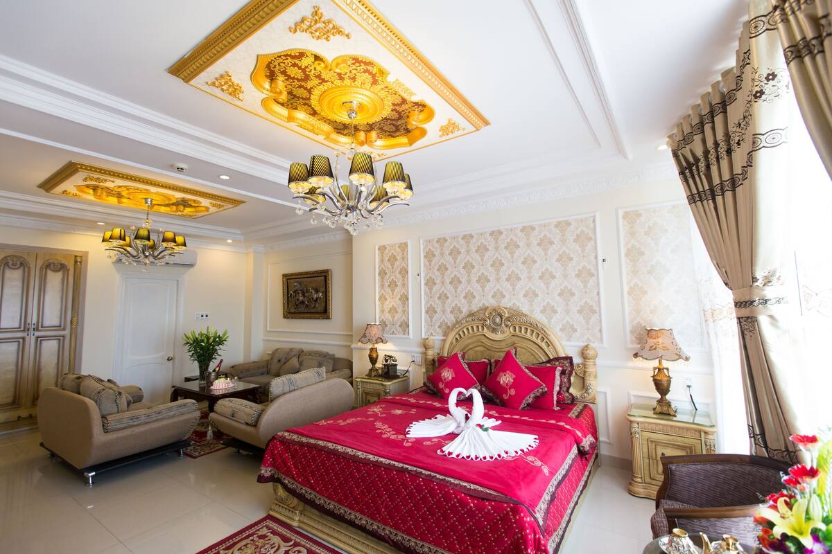 A luxurious bedroom with a large bed, a chandelier, and a classic design.
