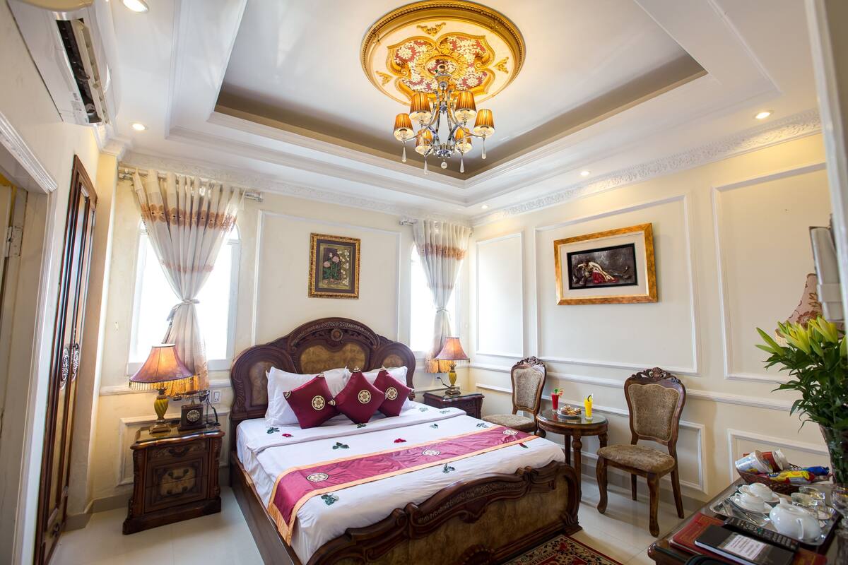 A well-appointed bedroom with a large bed, ornate ceiling, and classic decor.
