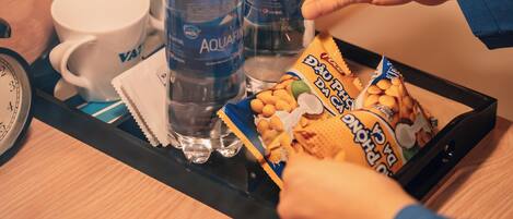 A tray with water bottles, a mug, and snack packets on a wooden surface.