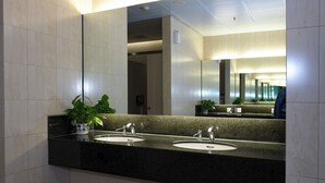 Une salle de bain moderne avec deux lavabos, un grand miroir et une plante en pot.