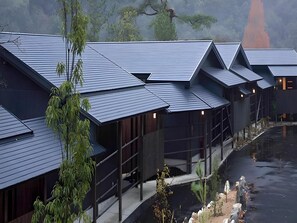 Eine Reihe von Gebäuden im traditionellen Stil mit dunklen Dächern und Holzbeschlägern, wahrscheinlich Teil eines Hotels oder Resorts.