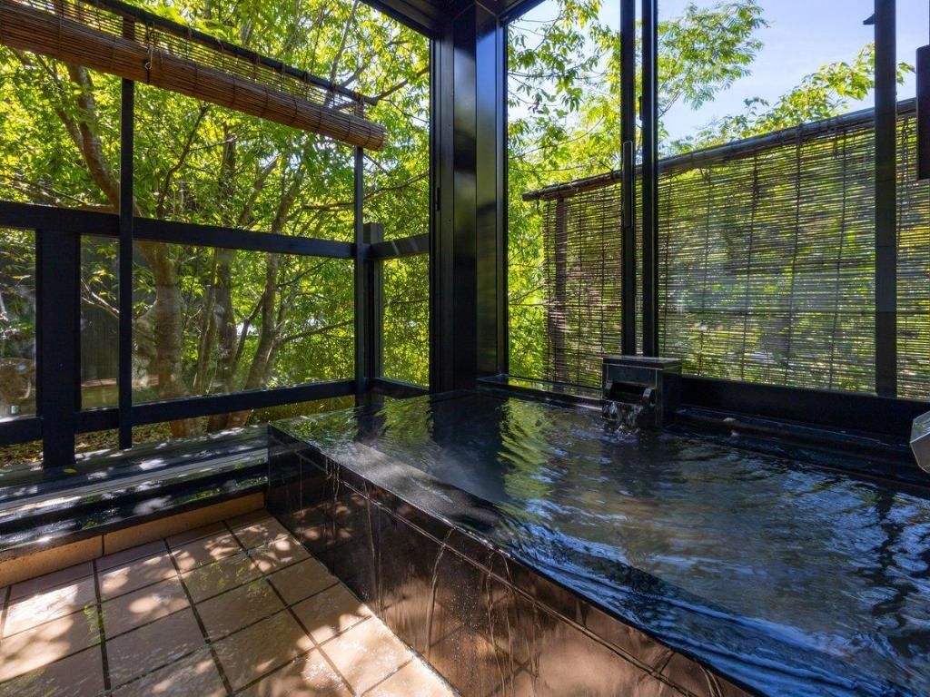A hot tub area with a view of trees through large windows.