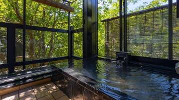 A hot tub area with a view of trees through large windows.