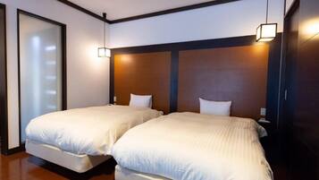 A hotel room with two beds, wooden headboards, and a sliding glass door.