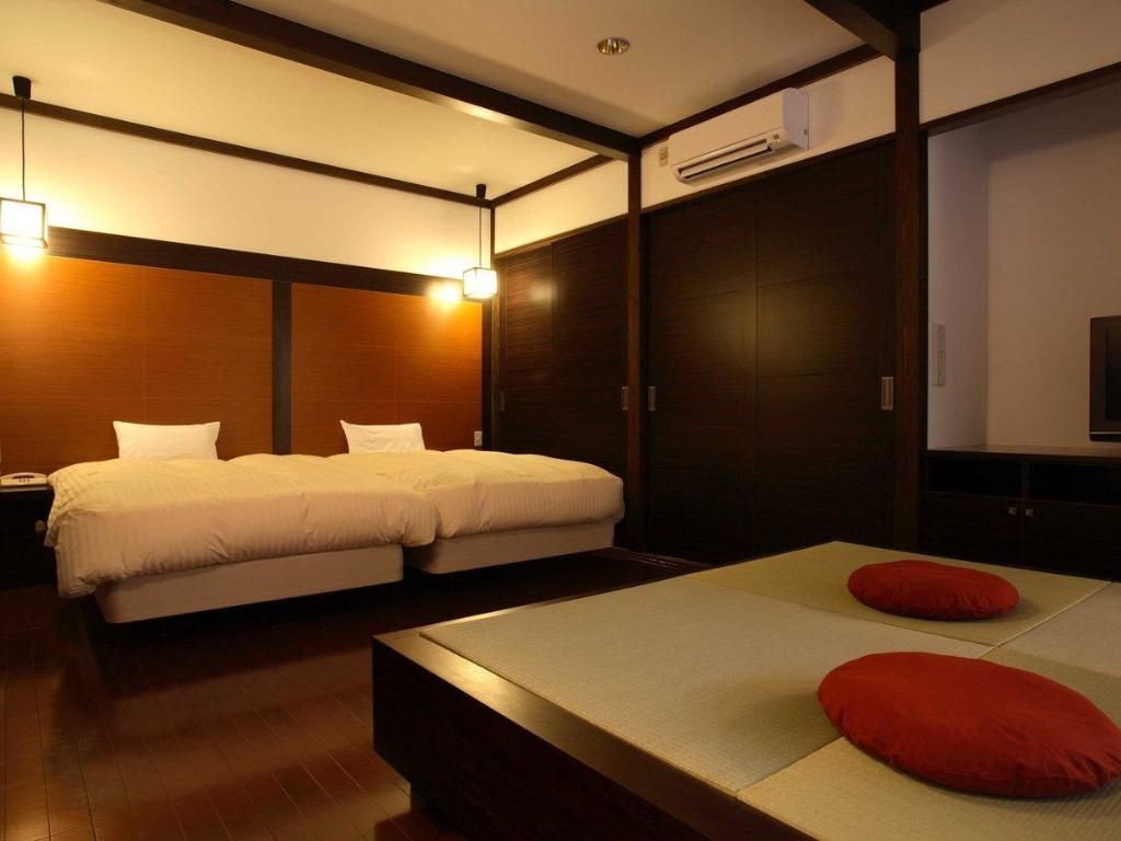 A hotel room with two beds, a small table, and a TV.