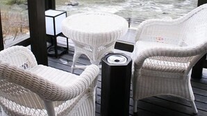 Un área de estar al aire libre techada con mobiliario de mimbre y vista al río.