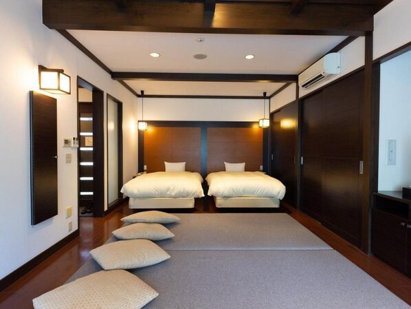 Een hotelkamer met twee bedden, een houten plafond en een groot raam.