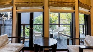 A covered outdoor seating area with a table and chairs, large windows, and a view of the outdoors.