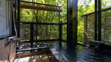 A hot tub area with a view of trees, a wooden bench, and a towel rack.