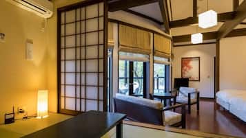 A traditional Japanese-style room with tatami flooring, a low table, a sofa, and a bed.