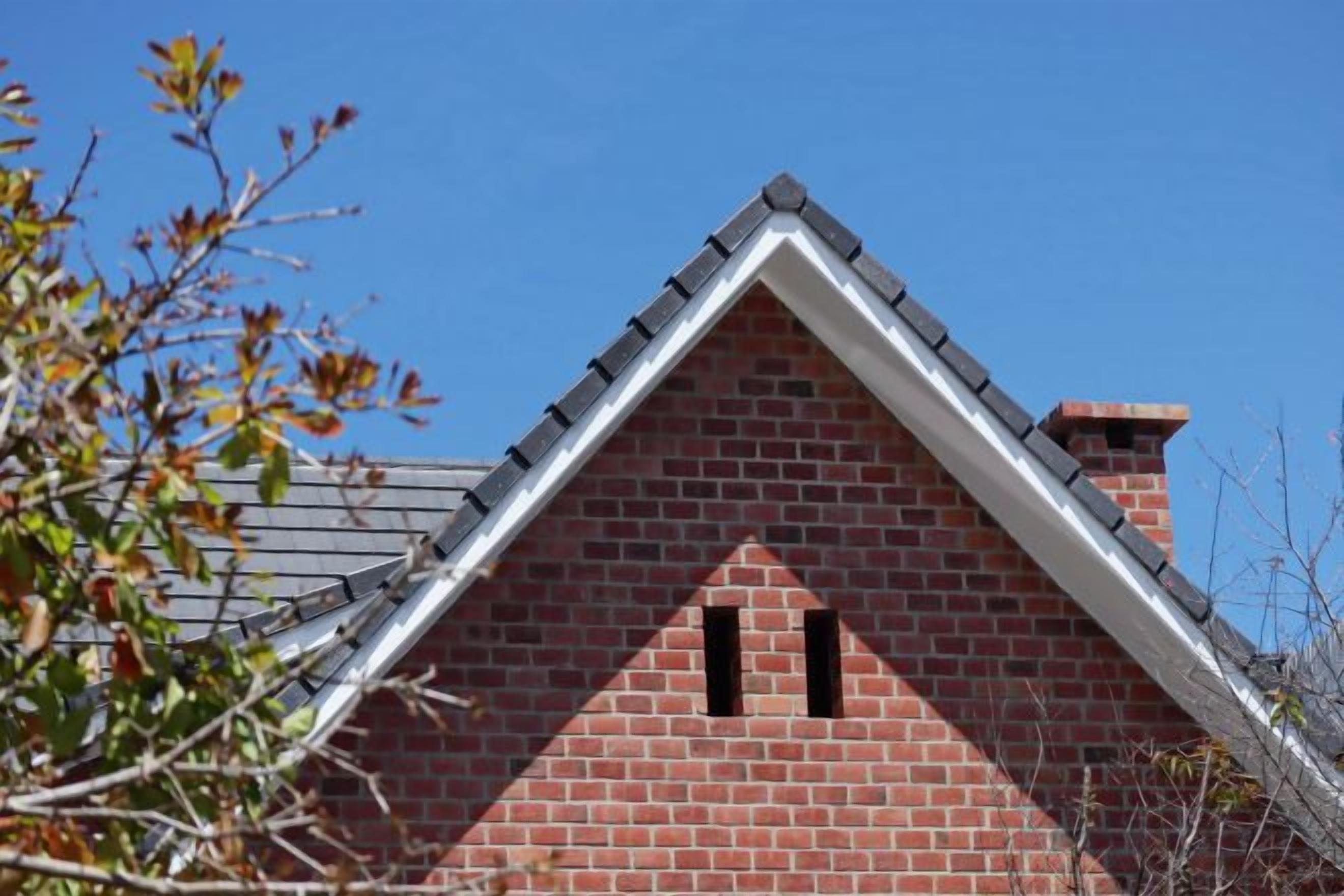 A red brick building with a gable roof and two small windows.