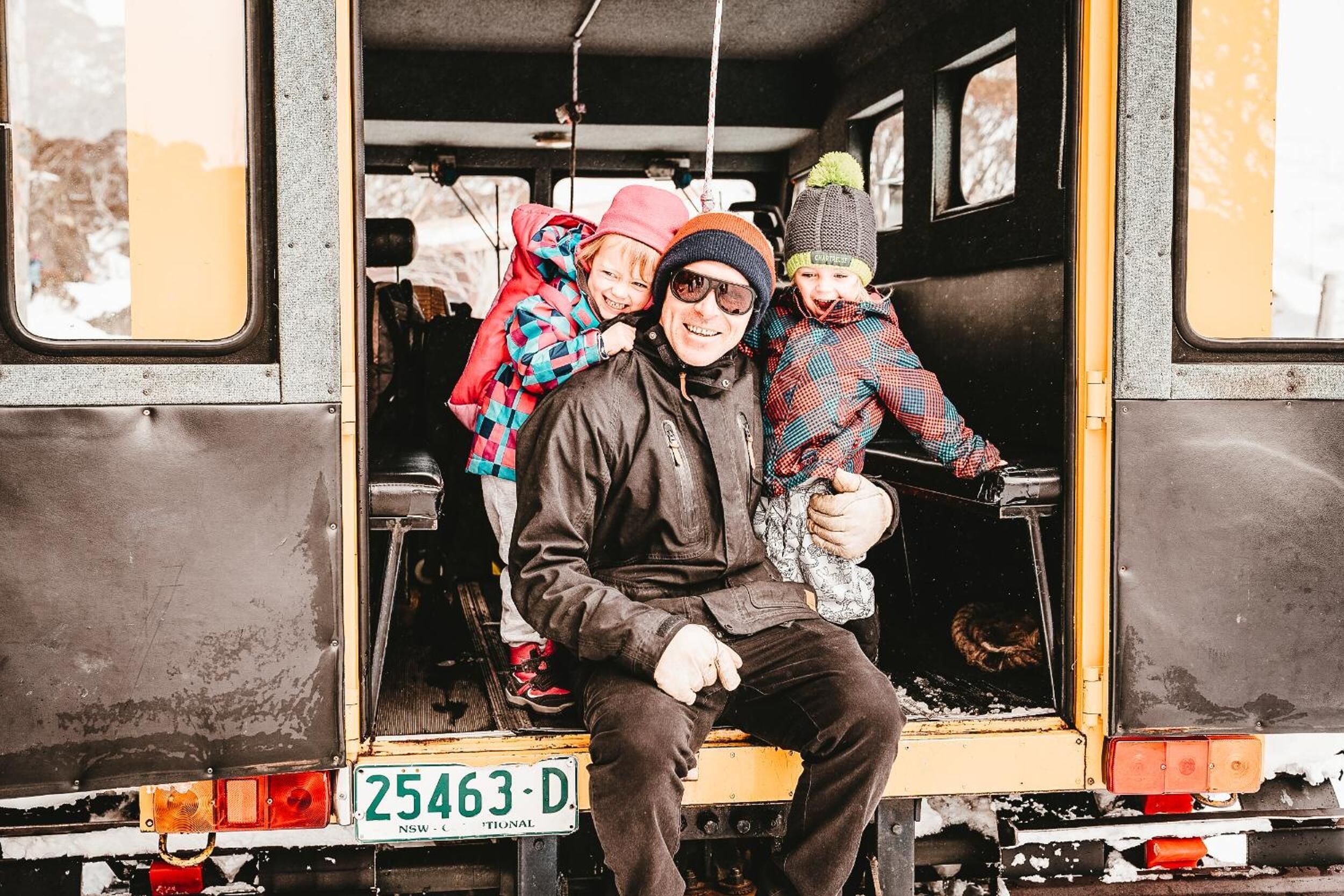 L'intérieur d'un véhicule, avec une personne assise sur le siège du conducteur, un enfant à l'arrière, et une plaque d'immatriculation visible.