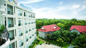 A multi-story hotel with balconies, surrounded by lush greenery and a clear sky. - Hoa Binh Phu Quoc Hotel (Phu Quoc)