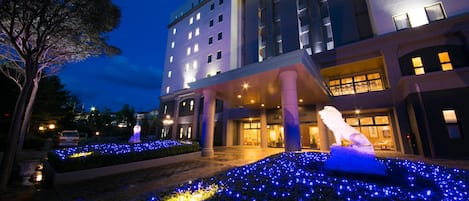 A hotel entrance with illuminated blue lights and a statue.