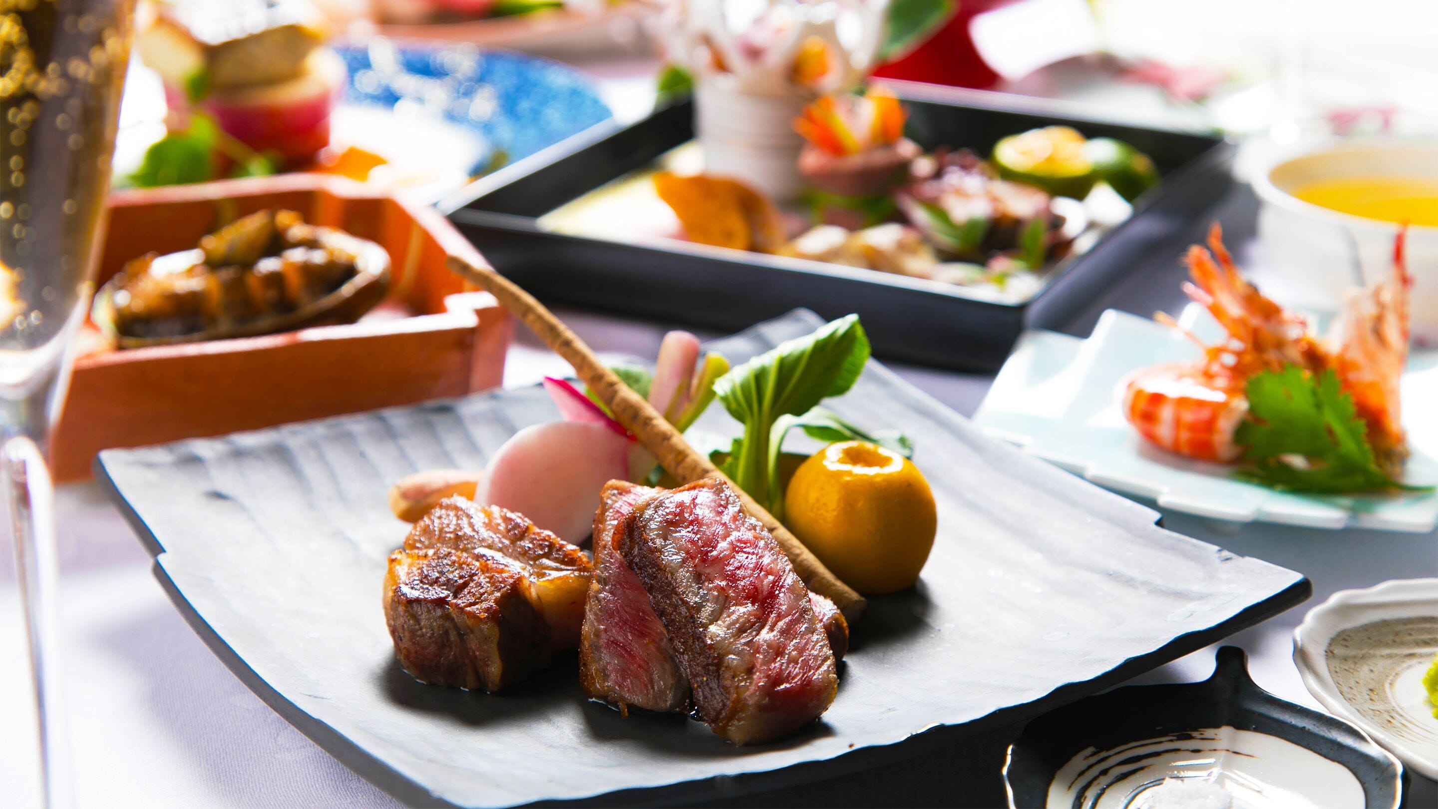 Une variété de plats, notamment de la viande grillée, des crevettes et des légumes, sont disposés sur une table.