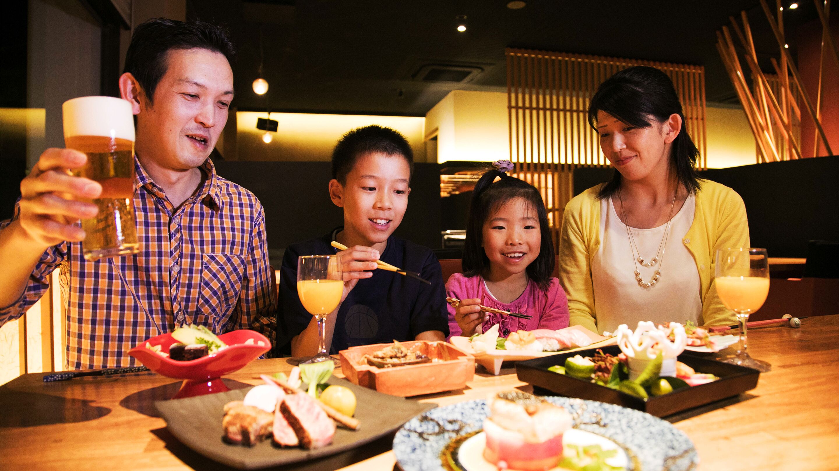 A group of people dining at a restaurant with various dishes and drinks on the table.