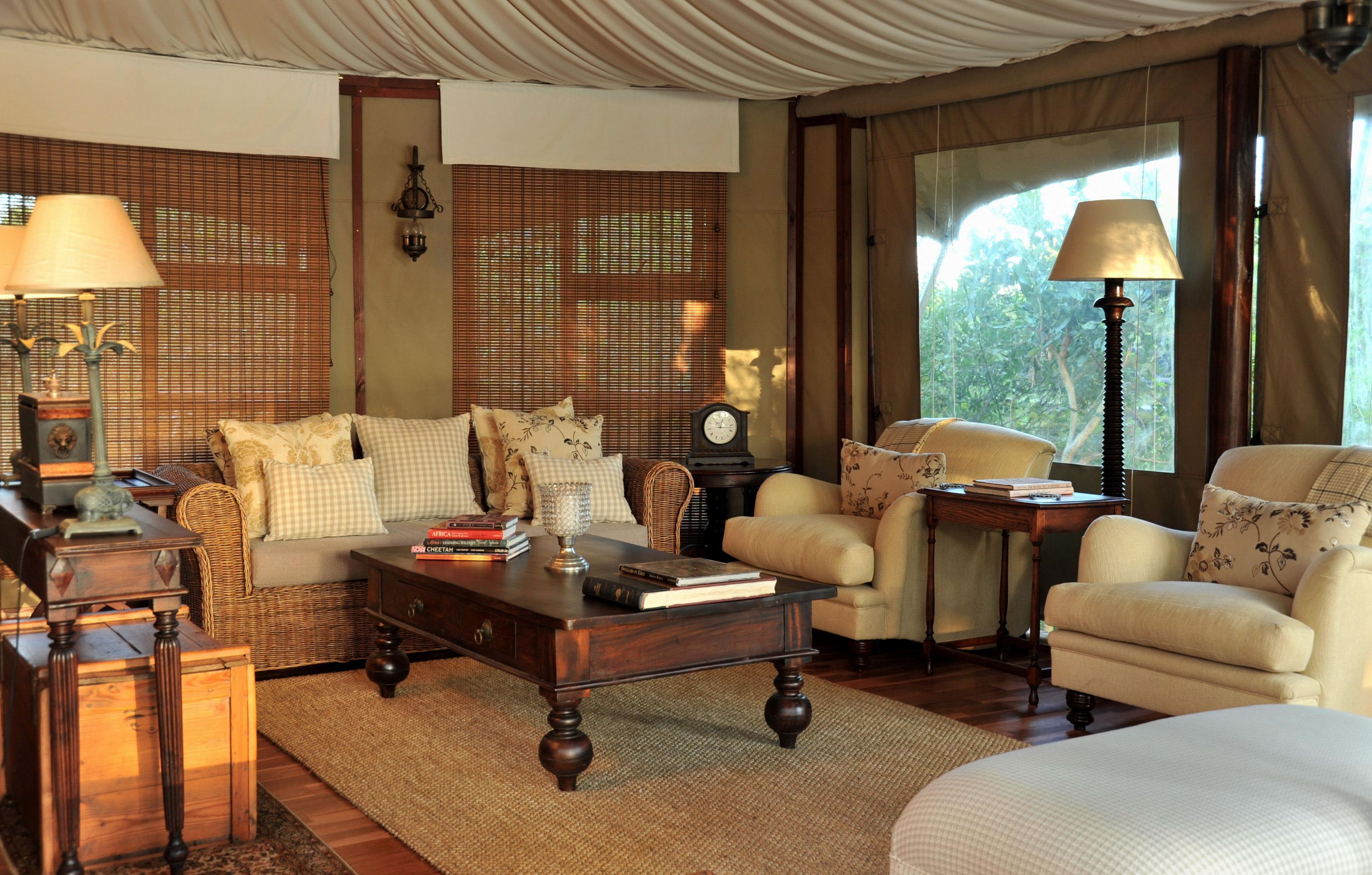 A well-furnished living room with a sofa, armchairs, a coffee table, and a side table with books.