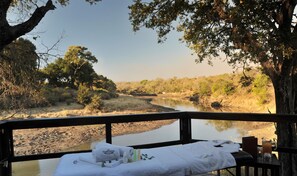 Vista de un río desde una terraza con una mesa dispuesta, incluyendo toallas y artículos de aseo.