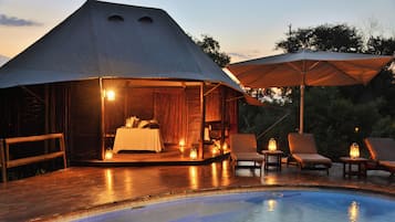 Alojamiento con tiendas de campaña, piscina, terraza de madera y mobiliario exterior.