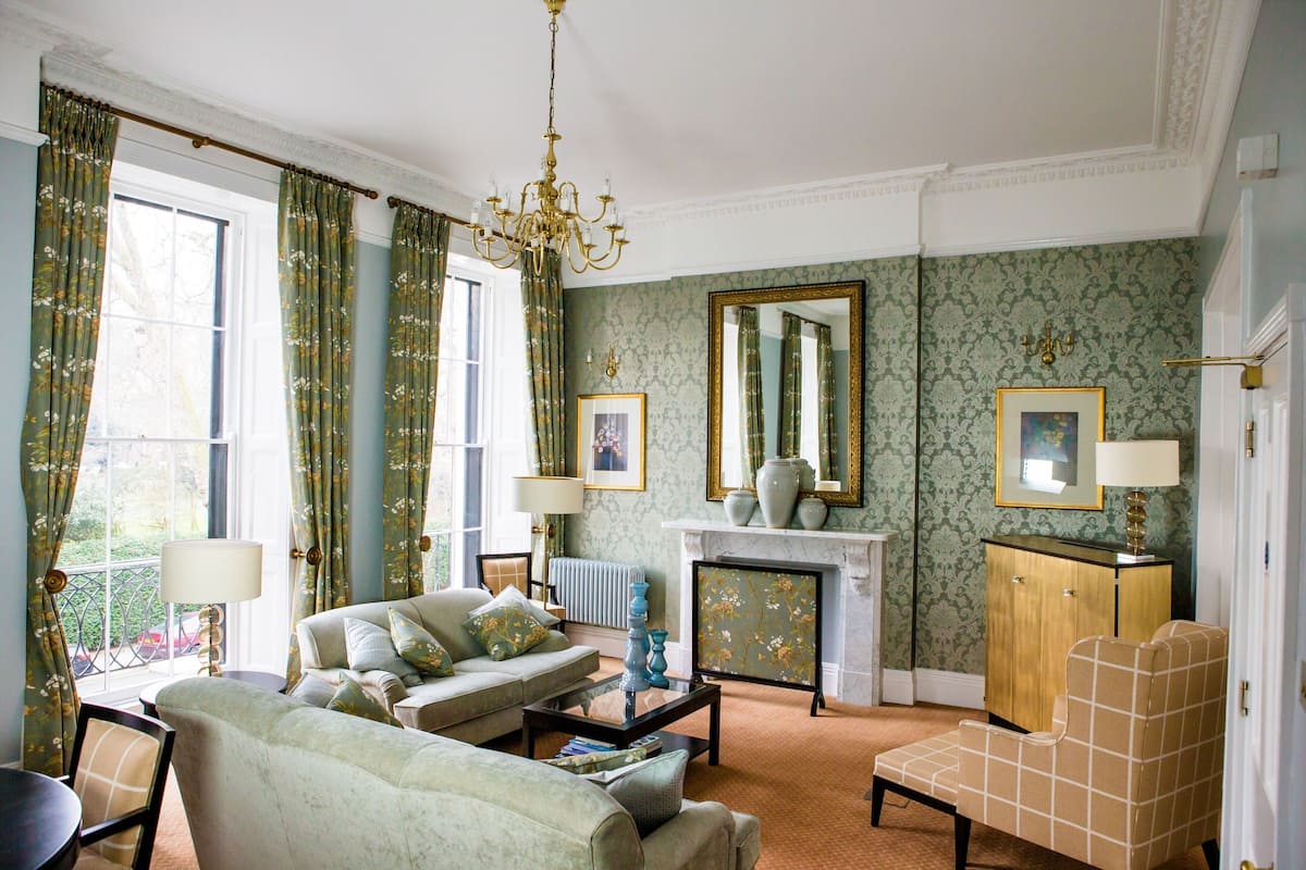 Ein traditionell eingerichtetes Wohnzimmer mit einer Couch, Sesseln, einem Couchtisch und einem Kamin.