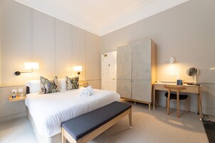 Ein Hotelzimmer mit einem großen Bett, Nachttischlampen, einem Schreibtisch und einem Kleiderschrank.