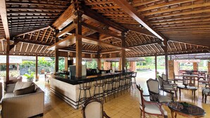 Un espacio al aire libre cubierto con un bar, asientos y vistas al jardín.