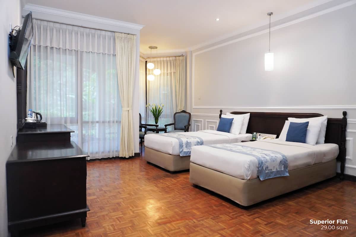 A hotel room with two beds, a desk, and a TV.