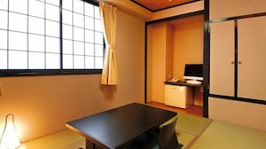 A traditional Japanese room with tatami flooring, a low table, a desk with a computer, and sliding doors.
