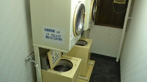 A laundry facility with a sign indicating a 50 yen fee for washing machines. - Hotel THE Grandcourt Matsusaka (Matsusaka)