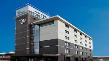 A multi-story hotel with a prominent sign on the corner, large windows, and a flat roof.