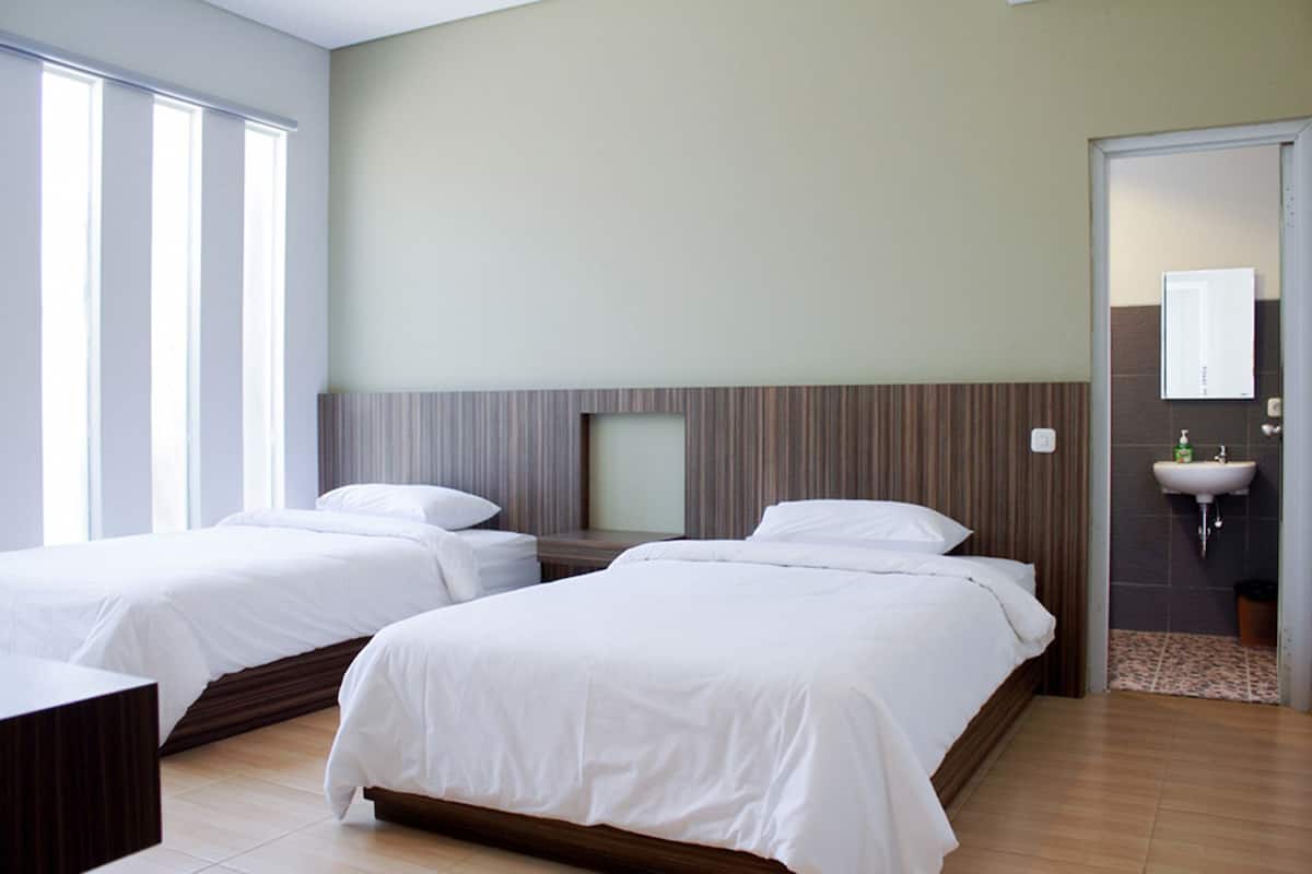 A hotel room with two beds, a large window, a bathroom with a sink, and a mirror.